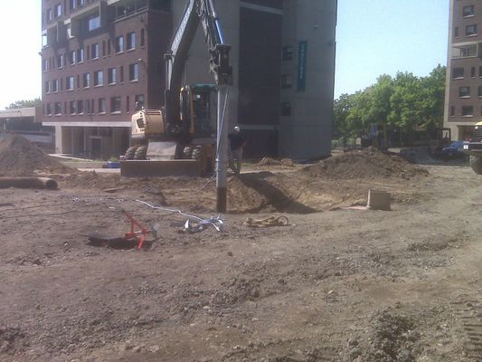 A construction site showing the excavator positioned near a newly dug trench with surrounding safety markers.