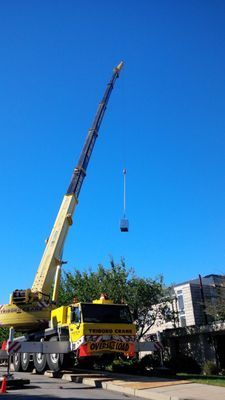 A long-distance shot of a crane boom suspending a piece of equipment during a high-rise installation.