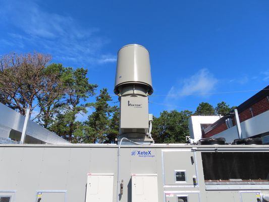 A close-up of a specialized cylindrical exhaust vent or filtration component mounted on a large rooftop mechanical unit.