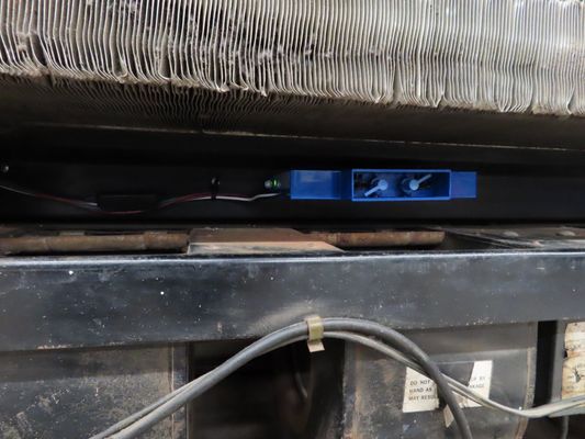 A detailed view of the blue blower motor assembly and copper piping inside a commercial air conditioning unit.