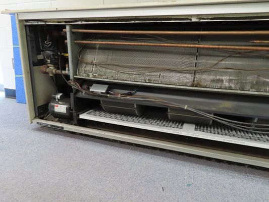 Close-up of an open HVAC cabinet revealing the evaporator coils and drainage tray during a maintenance check.