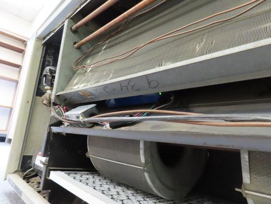 Internal view of a disassembled HVAC unit showing the blower fan, copper coils, and various electrical wiring.