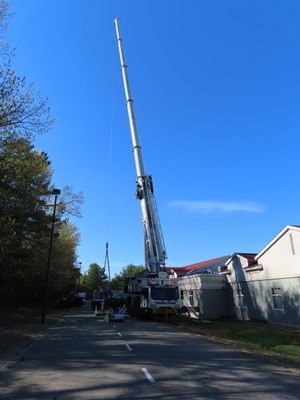 The long boom of a mobile crane stretching high into the sky above a commercial building.