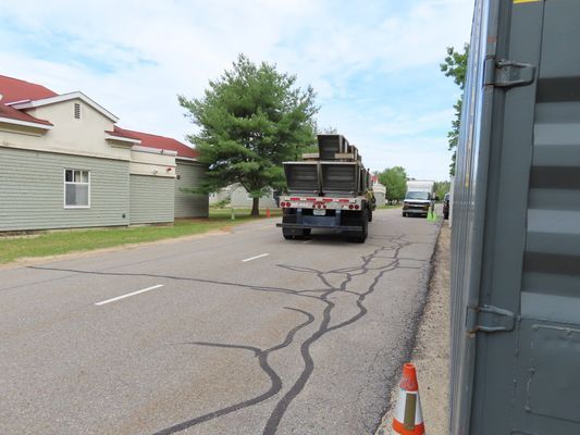 A rear view of the flatbed truck transporting industrial equipment along a paved road.