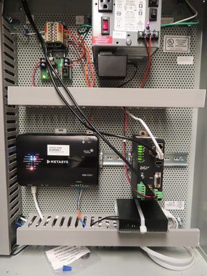 An open metal cabinet housing a modem, circuit boards, and organized wiring.