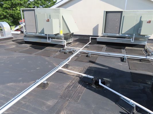 Angled view of rooftop air handlers and connecting utility lines.