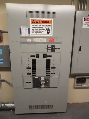 Close-up of a circuit breaker panel showing multiple switches and warning signs.