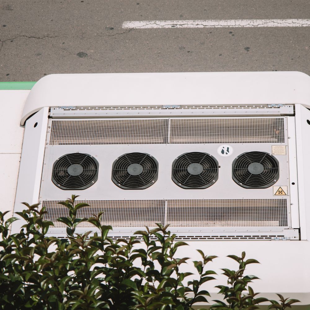 Overhead view of a commercial refrigeration condenser with four axial cooling fans and protective grilles.