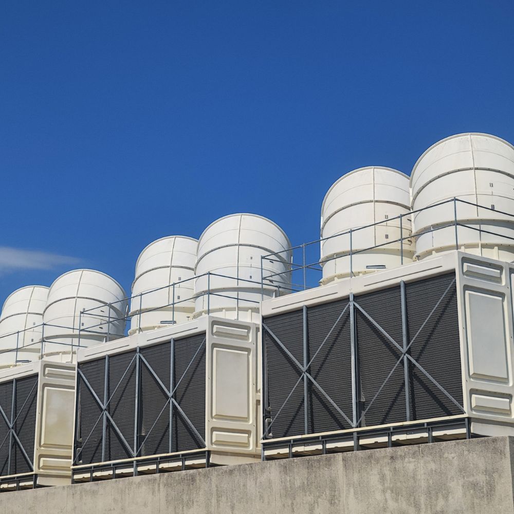 Large-scale industrial cooling towers mounted on a rooftop under a clear blue sky