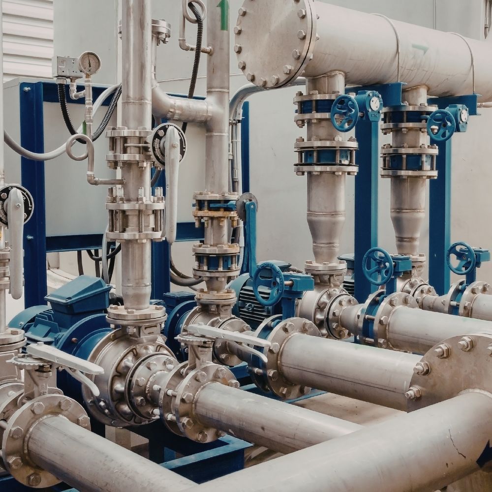 Industrial centrifugal pump station featuring stainless steel piping and blue manual butterfly valves.