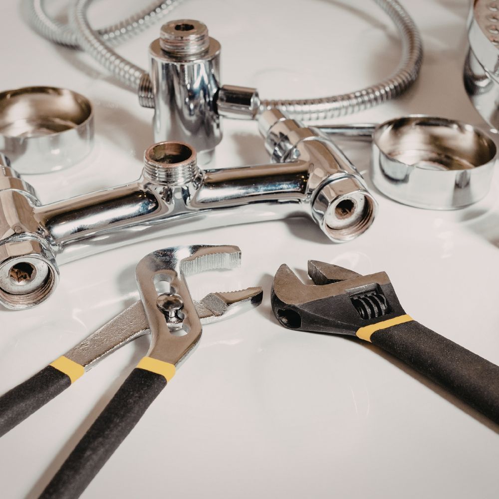High-polish chrome bathroom fixtures laid out with adjustable wrenches for a new installation.