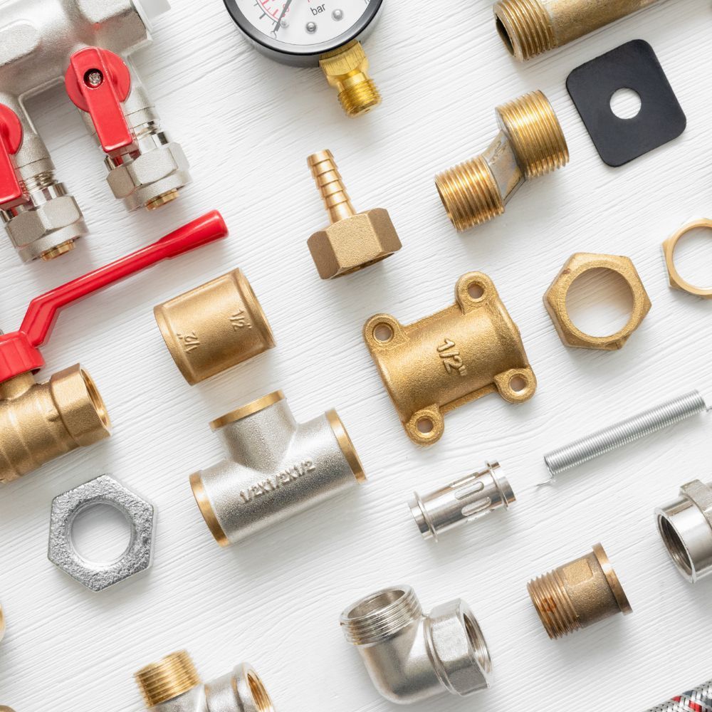 Flat lay of various brass plumbing fittings, including ball valves, T-junctions, and connectors.