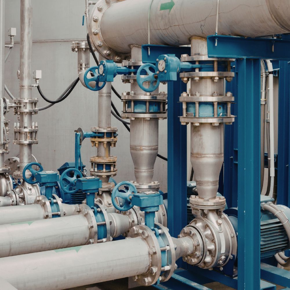 Close-up of mechanical pump flanges and blue control wheels on a commercial water distribution line.