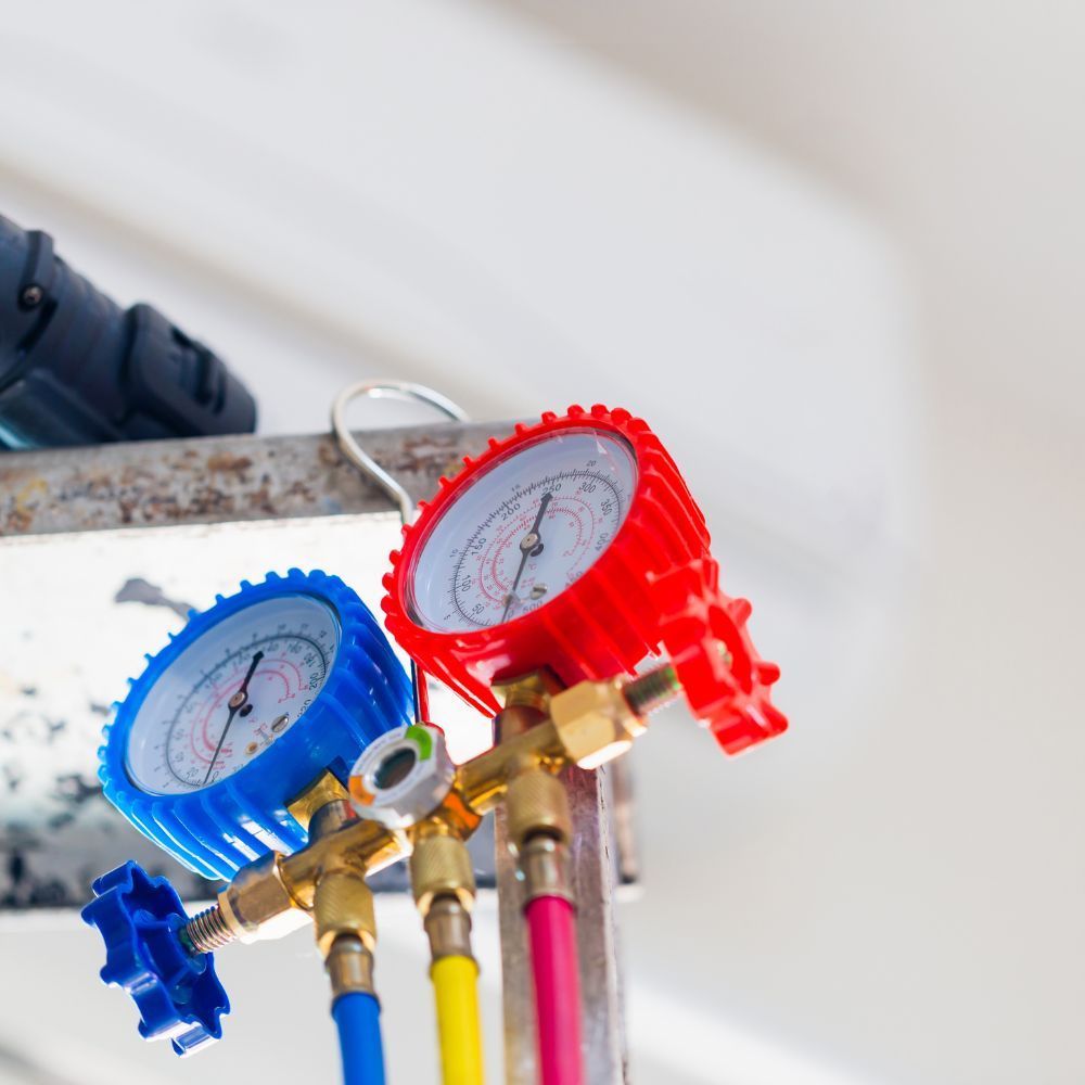Close-up of manifold pressure gauges connected to refrigerant lines for system testing.