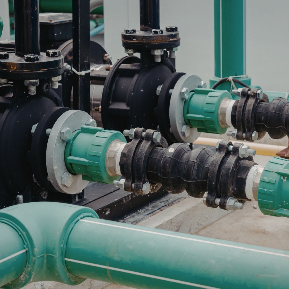 Heavy-duty flexible pipe couplings and green PVC elbows installed on a industrial filtration system.