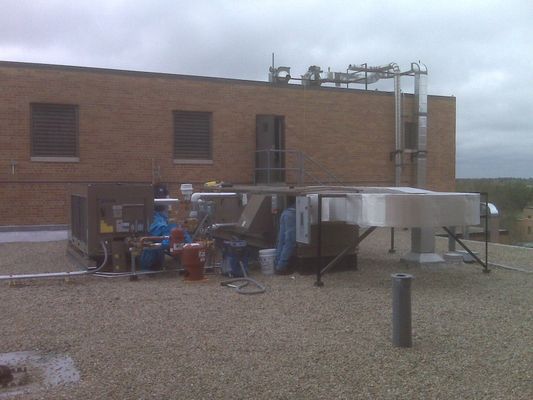 A rooftop HVAC installation featuring large metal ducting and equipment units on a gravel-covered roof.