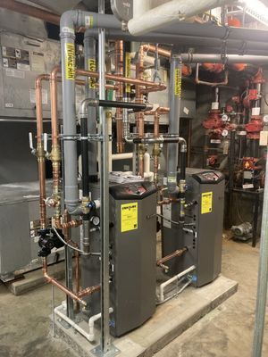 Indoor mechanical room featuring complex copper piping and vertical boilers.
