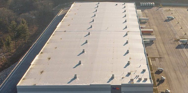 A close-up view of a flat, light-colored industrial roof with several small ventilation pipes.