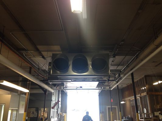 An interior view of an industrial garage or workshop with a large commercial air handler or filtration unit mounted to the ceiling.