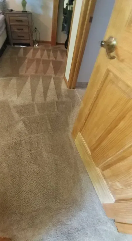 A bedroom with a carpeted floor and a wooden door.