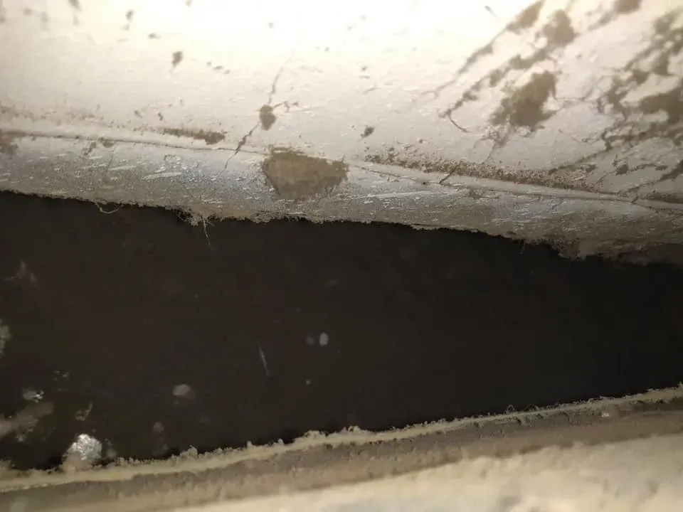 A close up of a dirty ceiling with a hole in it.