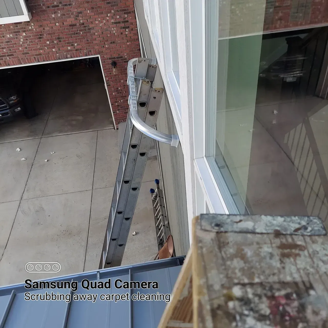 A ladder is attached to the side of a building taken by a samsung quad camera