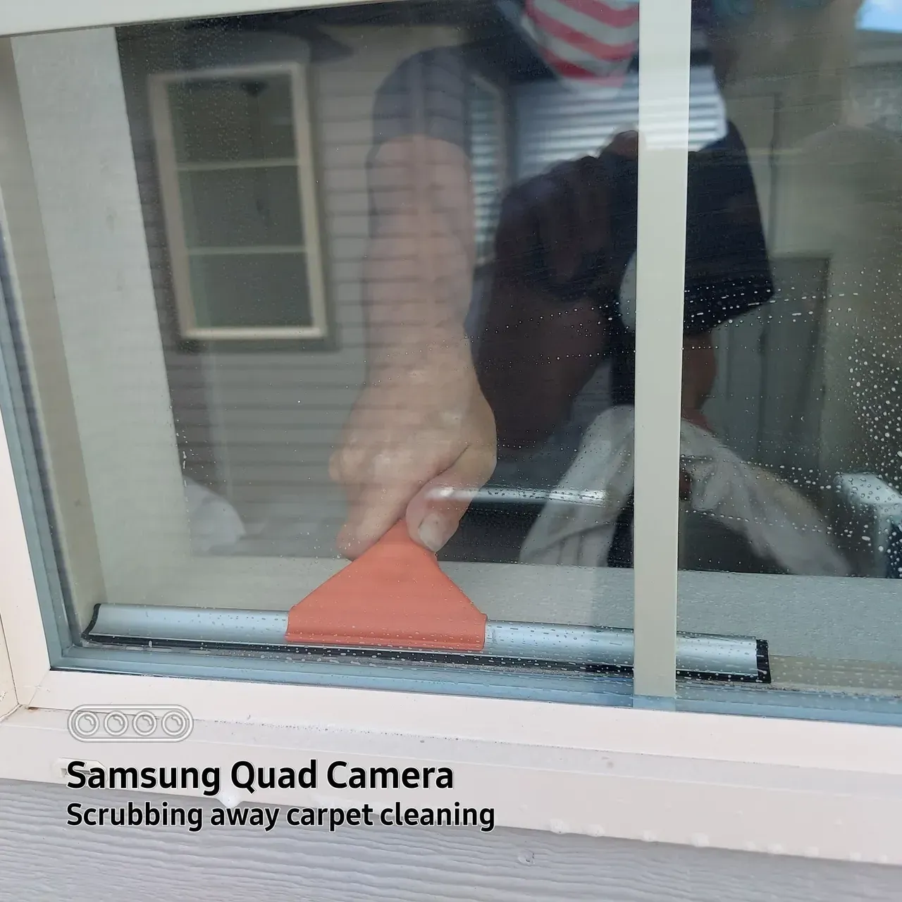 A person cleaning a window with a samsung quad camera