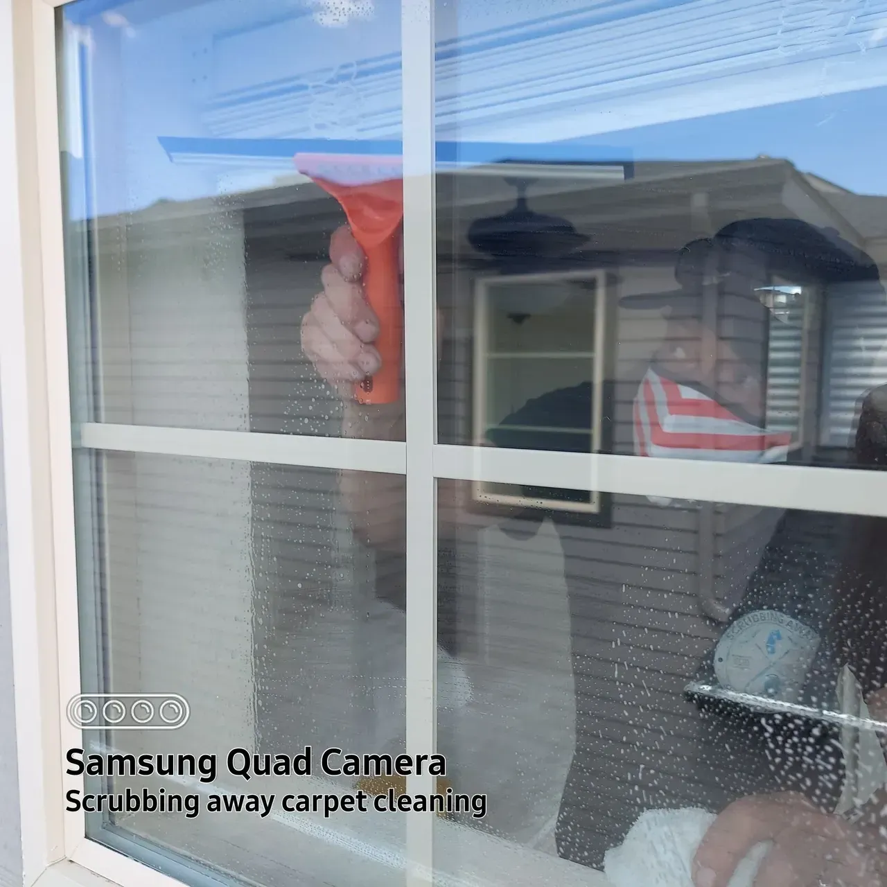 A person is cleaning a window with a samsung quad camera
