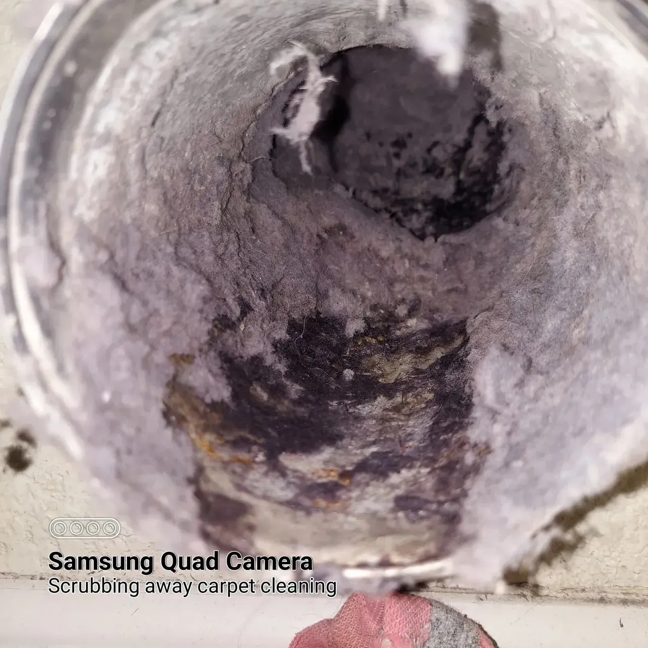 A samsung quad camera is taking a picture of a dirty drain