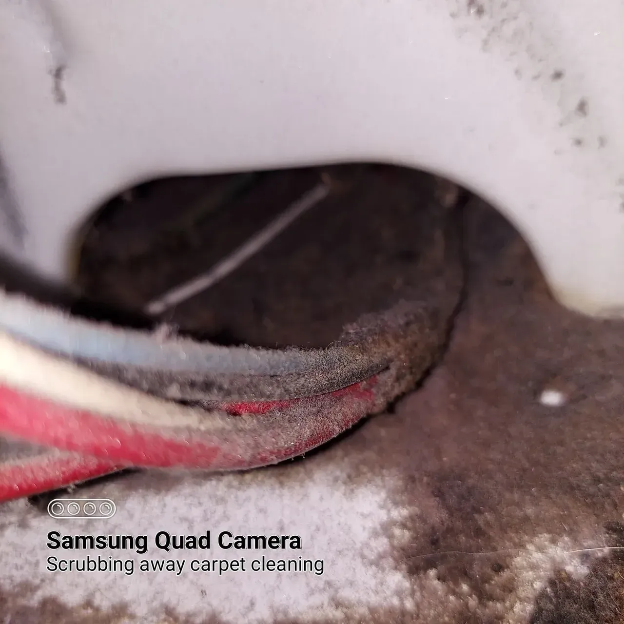 A samsung quad camera is taking a picture of a dirty carpet.