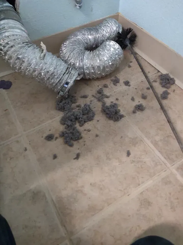 A duct is laying on the floor next to a broom.