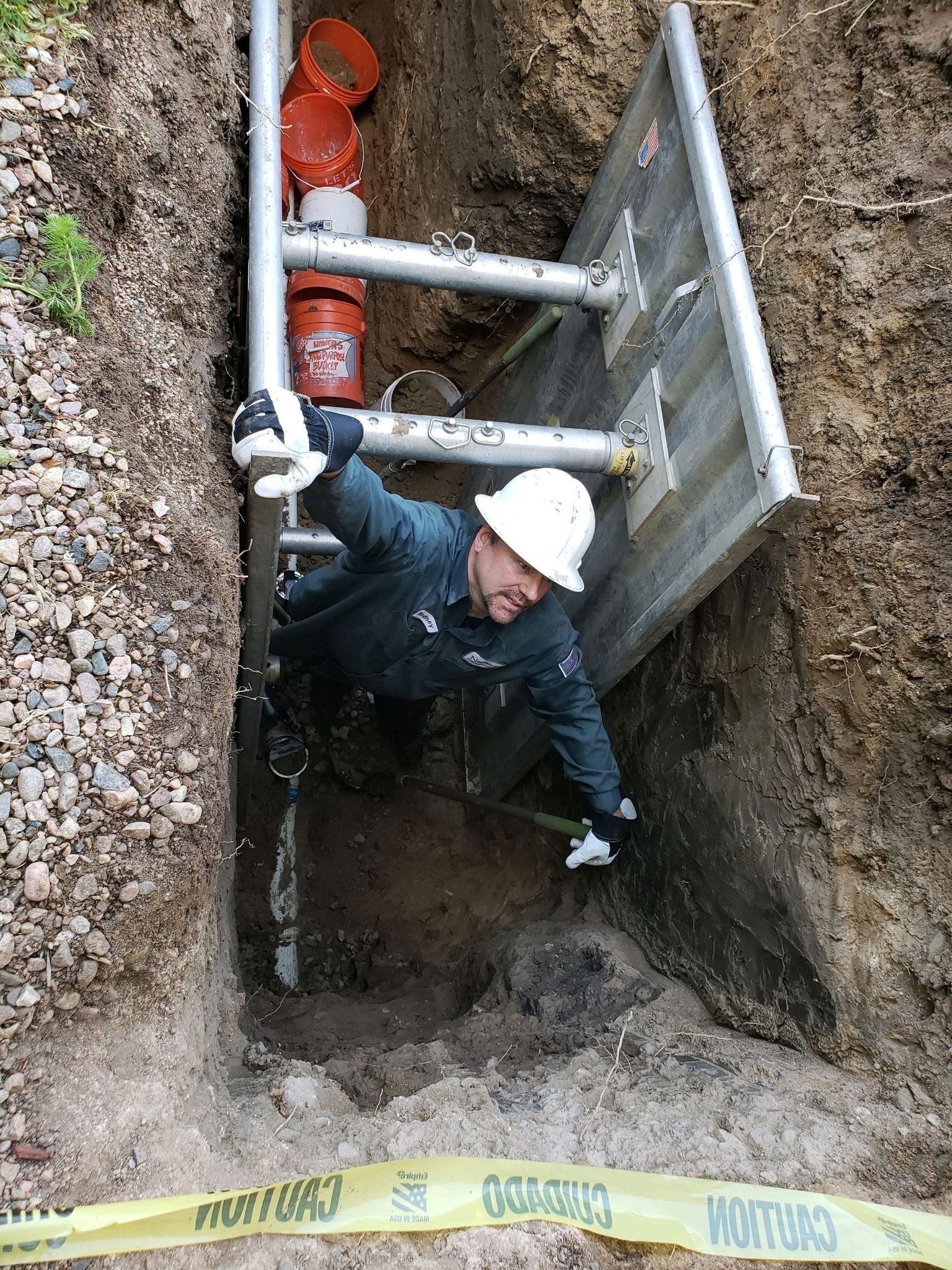 A man in a hard hat is climbing a ladder into a hole