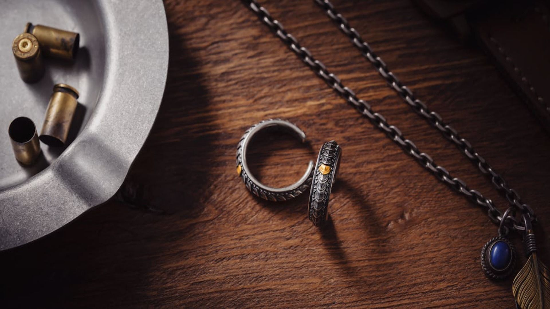 Un anillo, un collar y balas están sobre una mesa de madera.