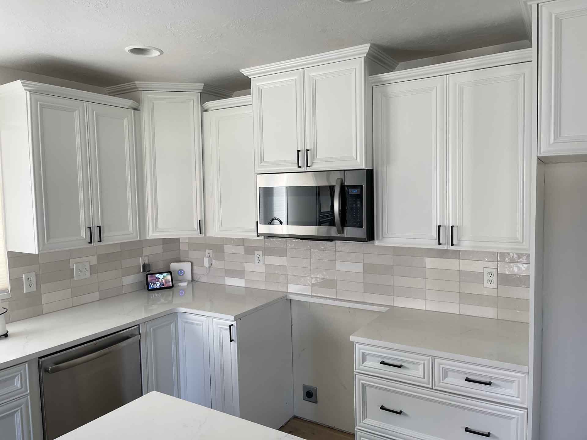 A kitchen with white cabinets , a microwave , and a dishwasher.