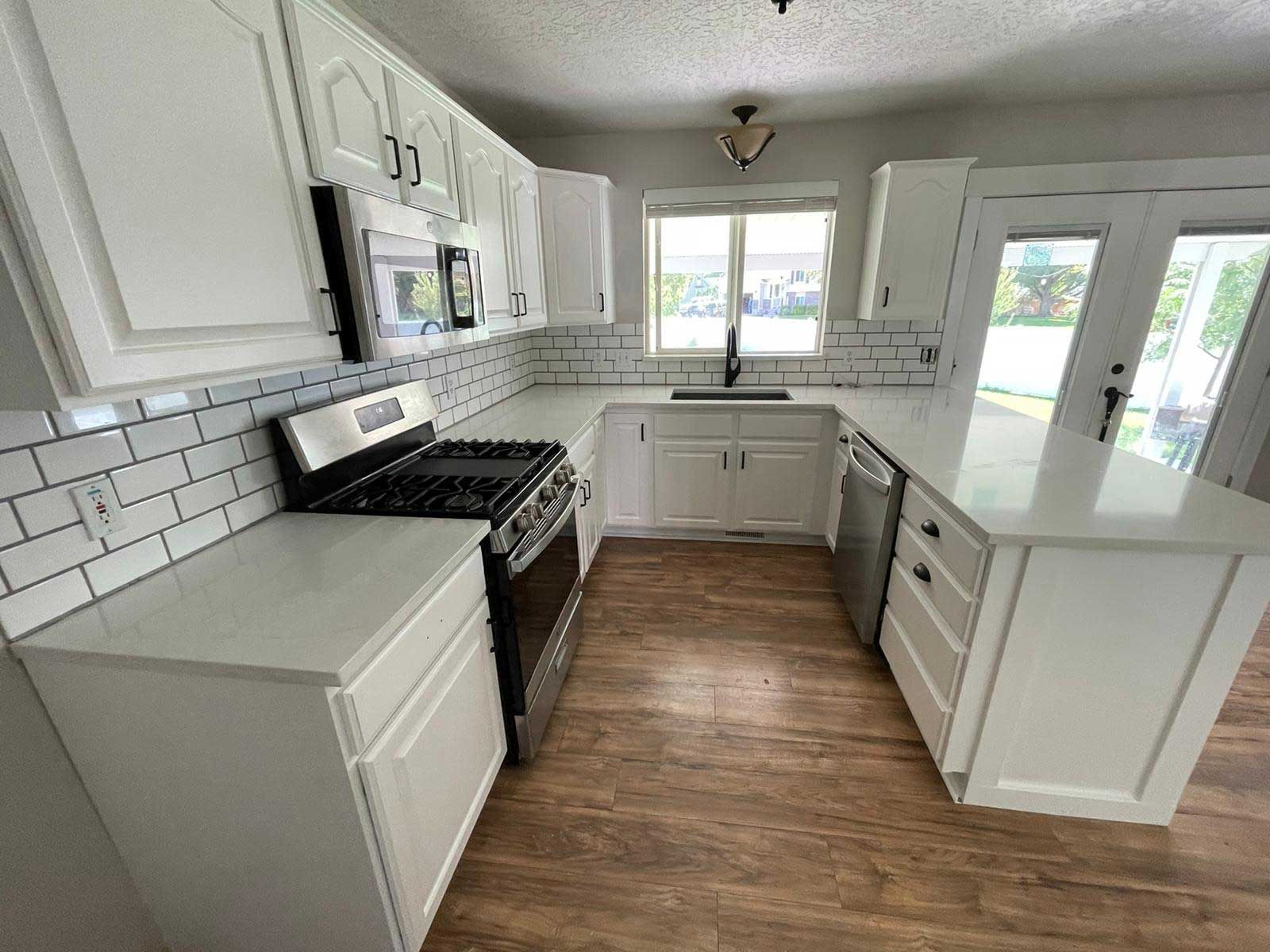 A kitchen with white cabinets , a stove and a sink.