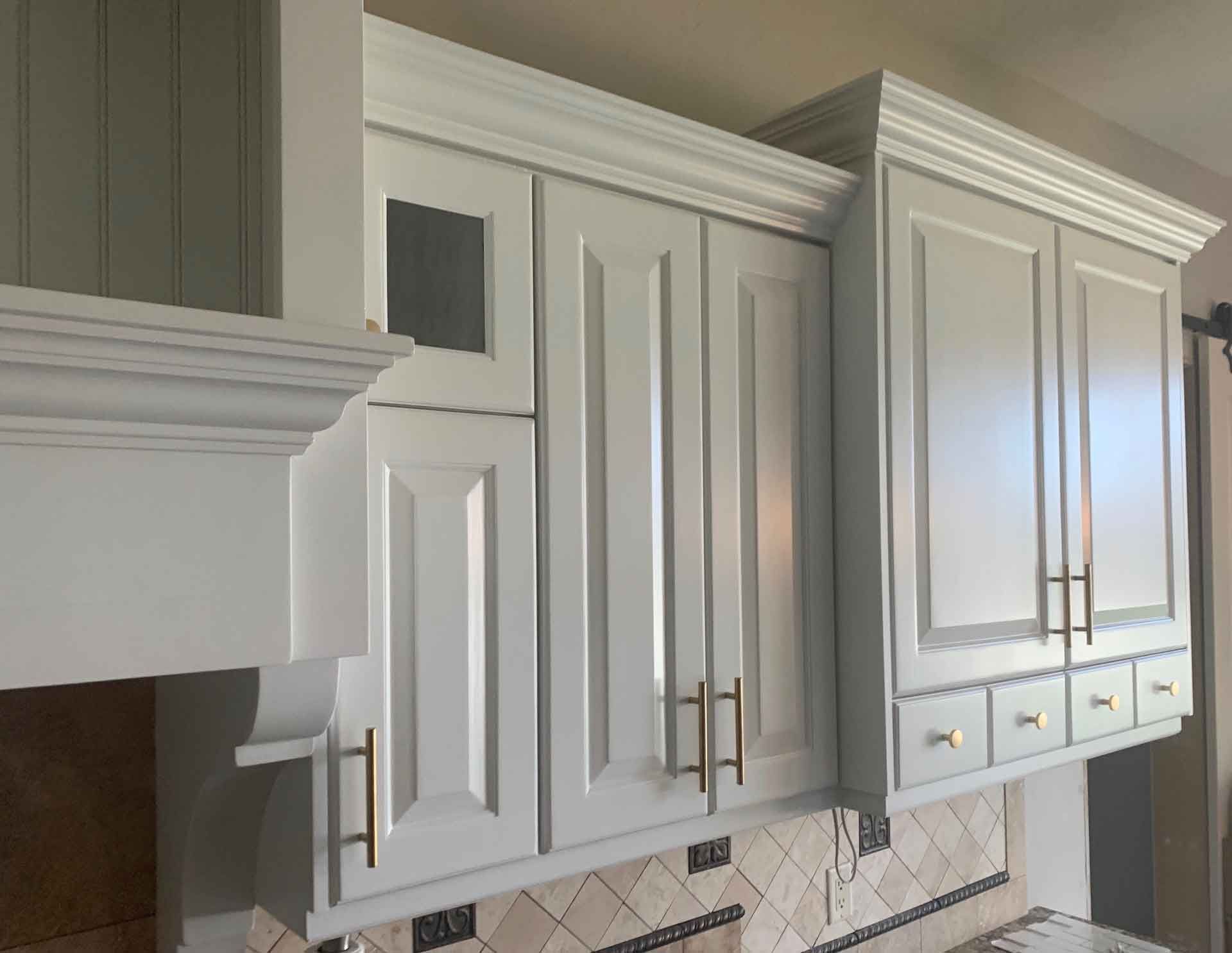 A kitchen with white cabinets and gold handles