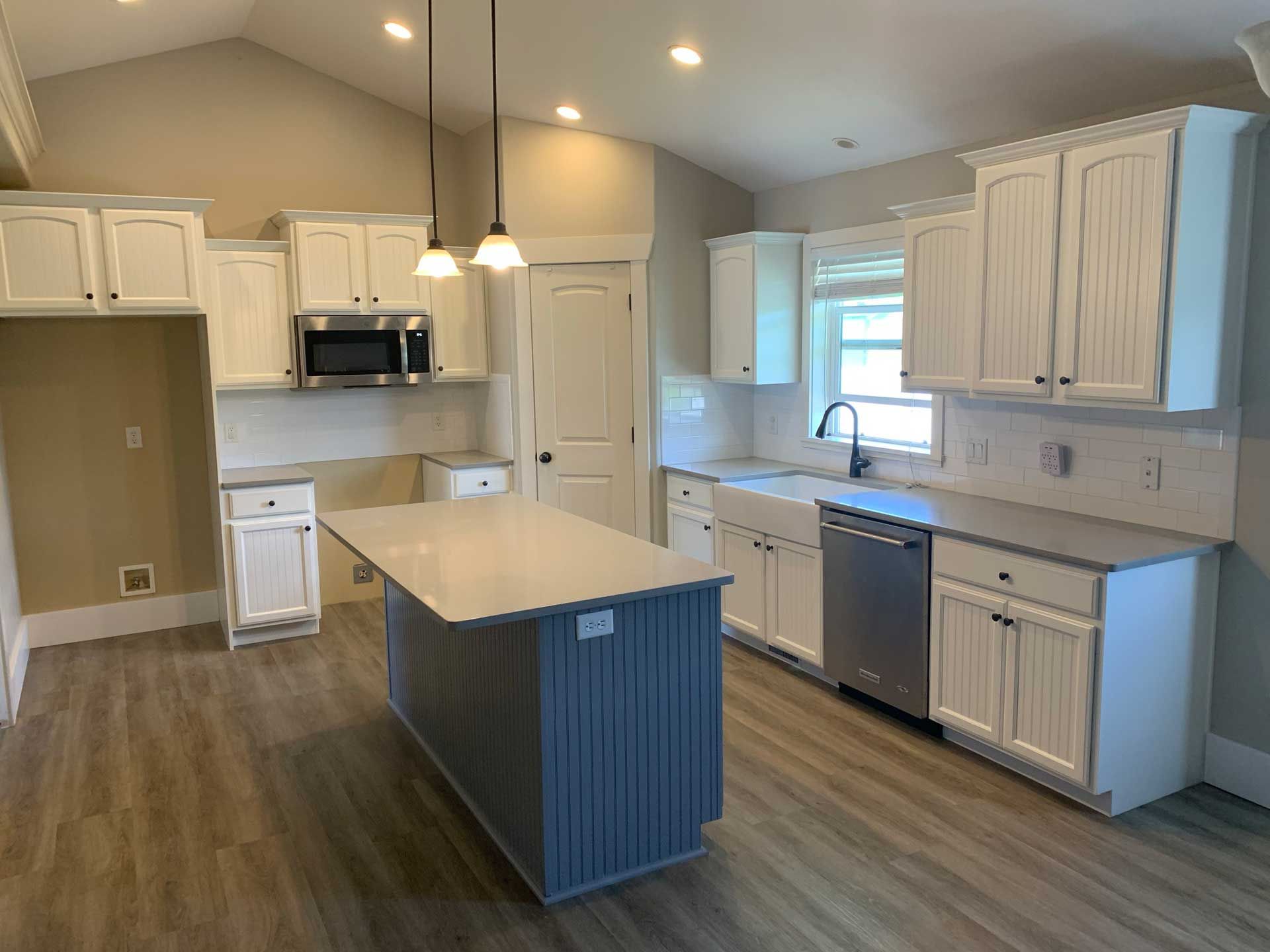 A kitchen with white cabinets , stainless steel appliances , and a large island.