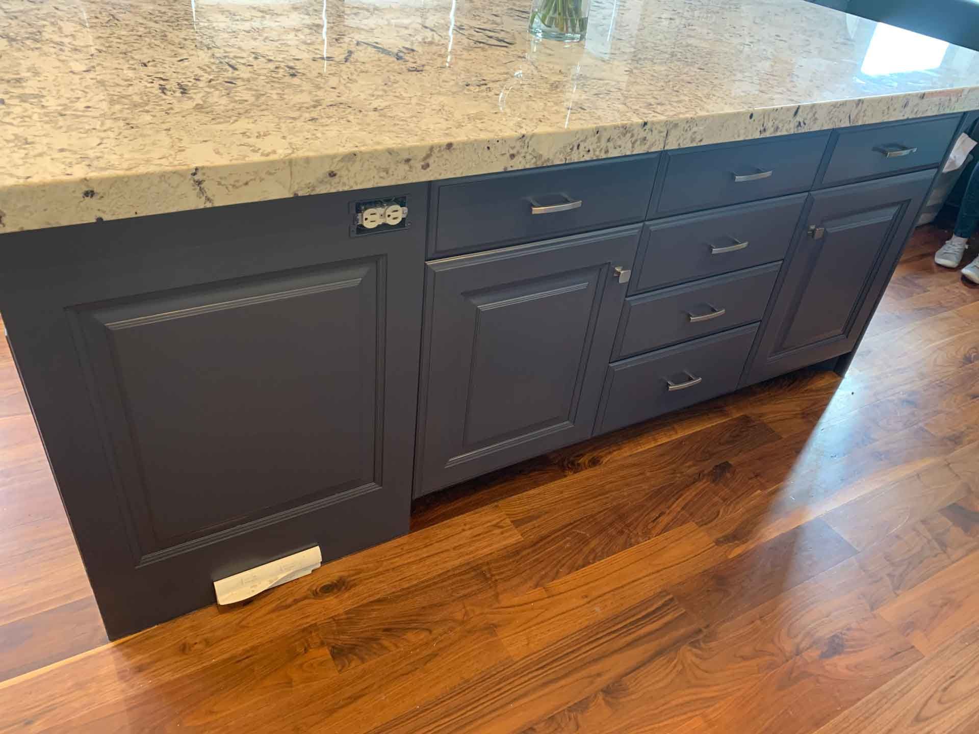 A kitchen island with blue cabinets and a granite counter top.