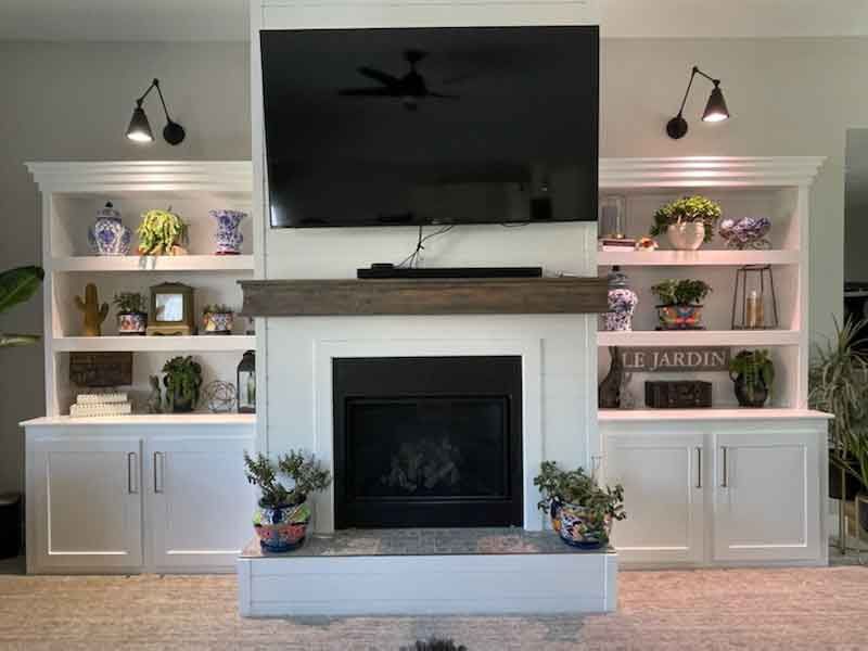 A living room with a fireplace , shelves , and a flat screen tv.