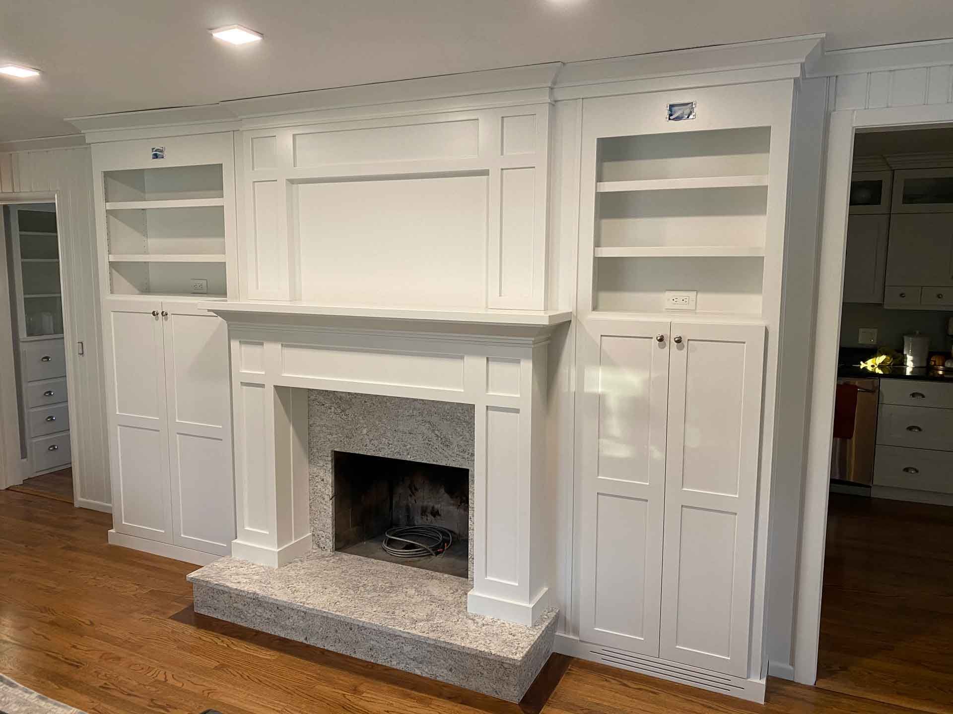 A living room with a fireplace and built in shelves.