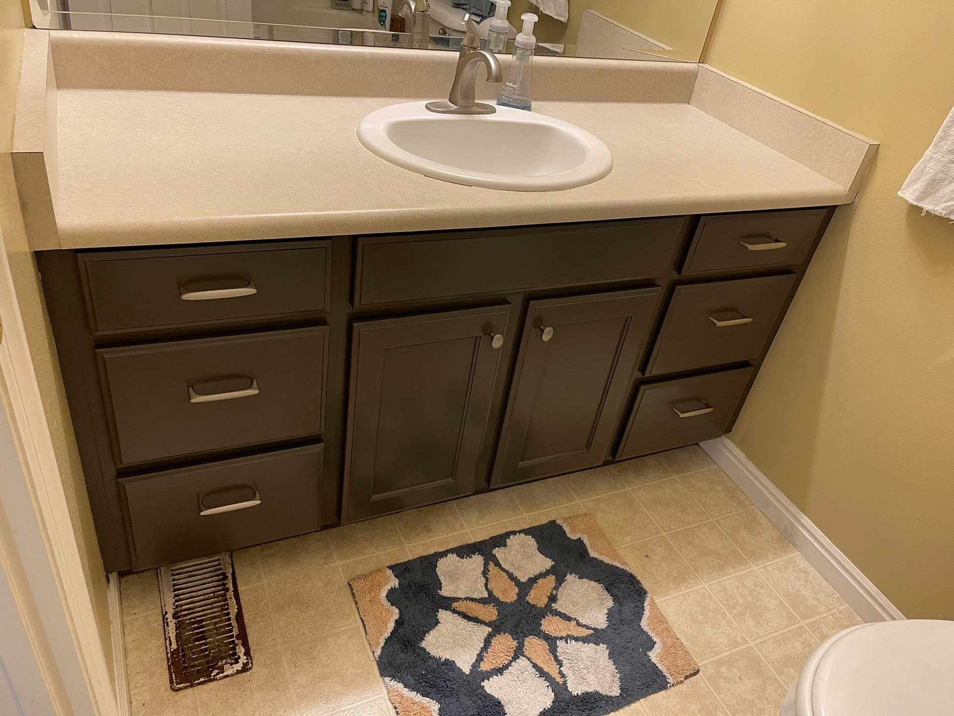 A bathroom with a sink , drawers , and a toilet.