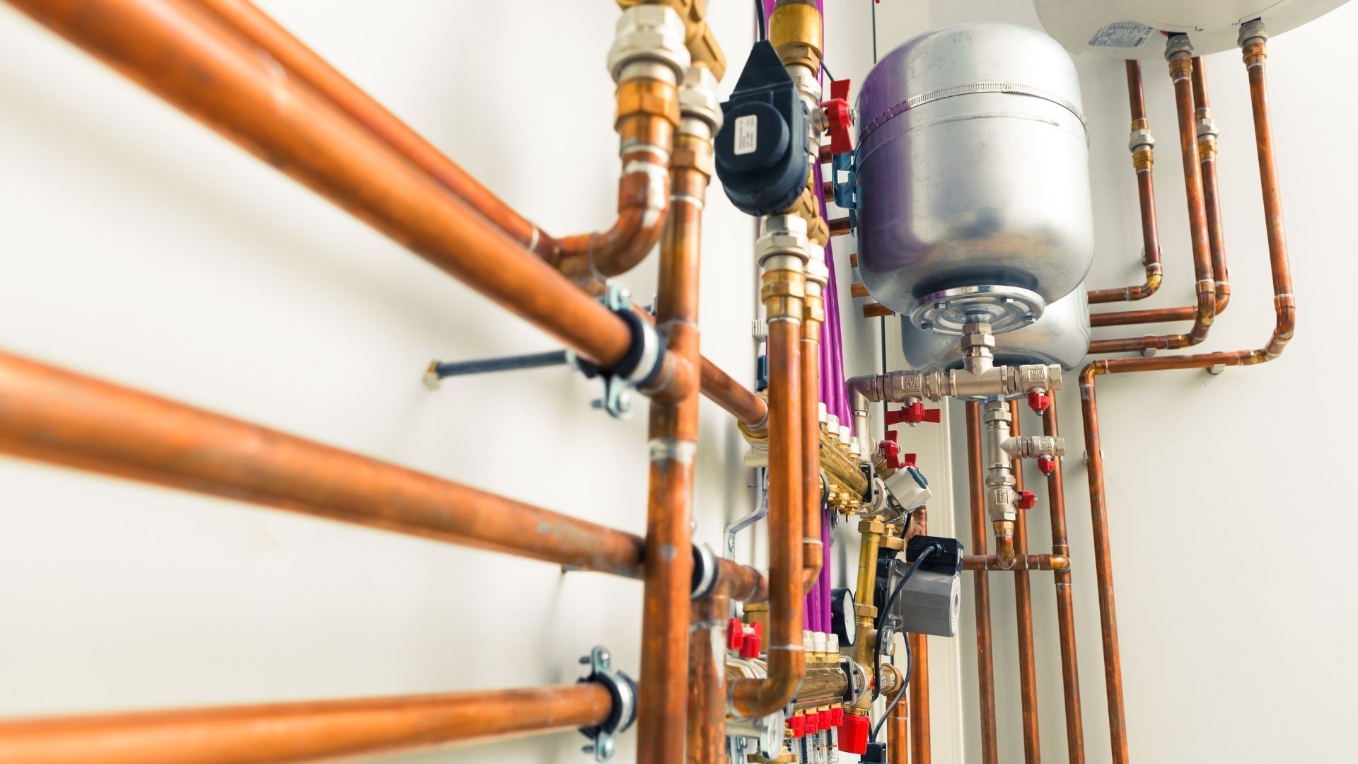 A row of copper pipes hanging from the ceiling in a room.