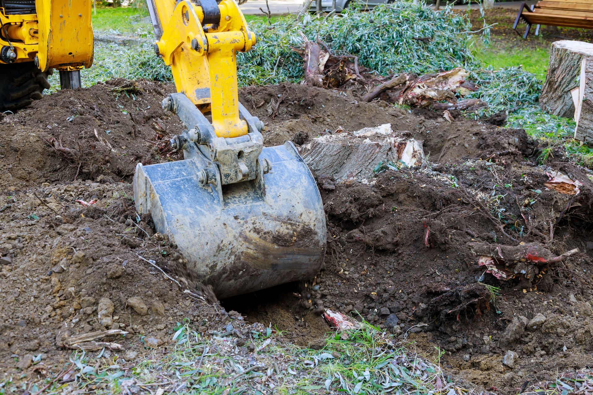 a backhoe bucket digging out a stump while trenching.