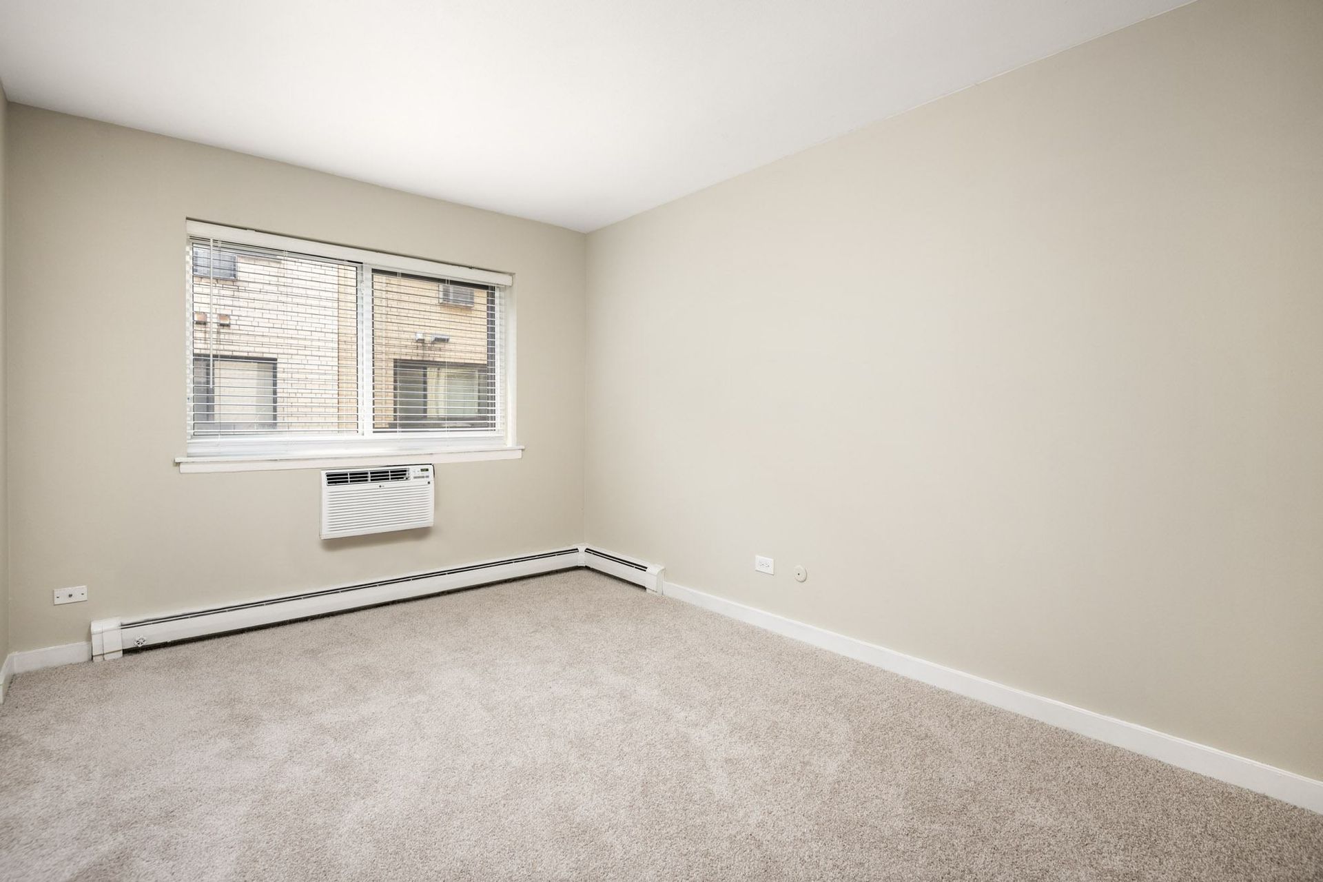 an empty room with a window and carpet