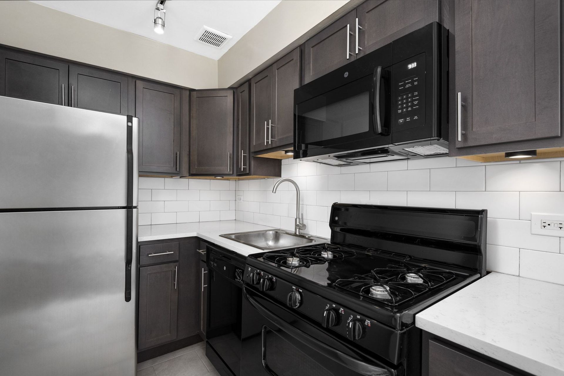 a kitchen with black and white appliances and a stainless steel refrigerator
