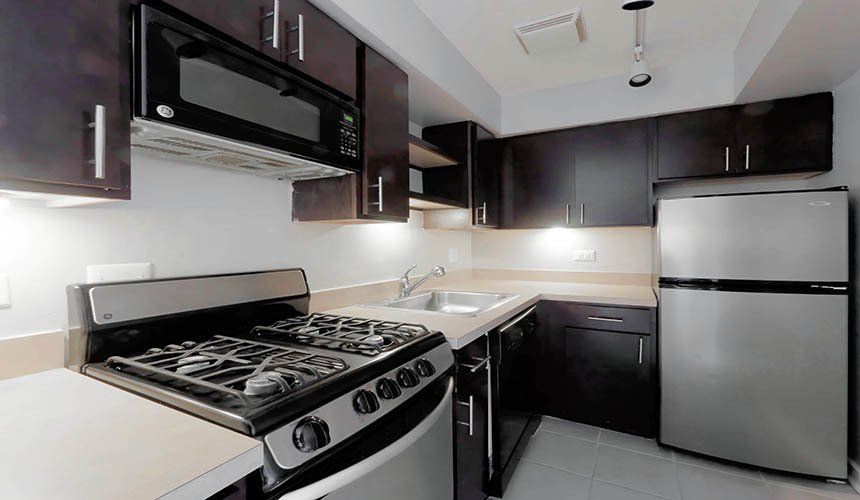 A kitchen with a stove, refrigerator, microwave, and sink at Reside on Roscoe in Lakeview. 