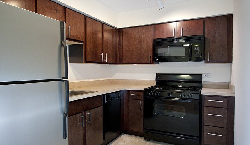 A kitchen with stainless steel appliances and wooden cabinets at Reside on Roscoe.
