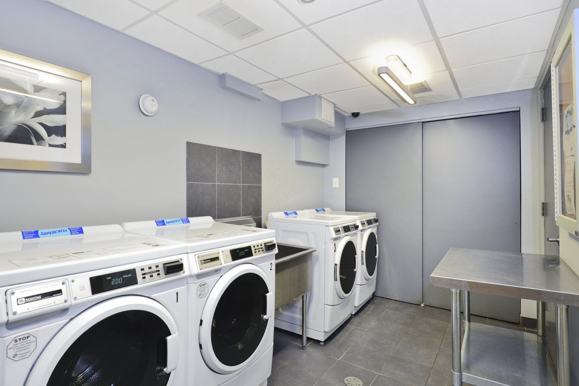 A laundry room with washers and dryers and a sink at Reside on Roscoe.