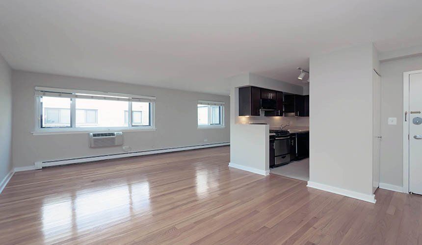 An empty apartment with hardwood floors and white walls at Reside on Roscoe.