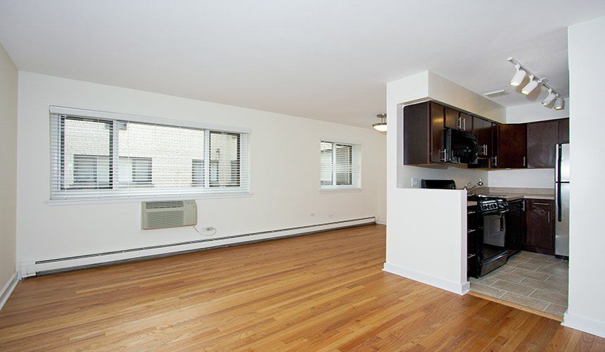 An empty apartment with hardwood floors and a kitchen at Reside on Roscoe.
